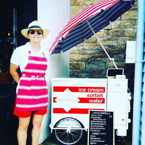 Ice cream and sorbet cart adorned with a red and white striped umbrella, showcasing various flavours on a menu, offered by PromoWheels for events and markets.